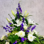 Grabgesteck in die Höhe mit weißen Blumen und blauen Akzenten